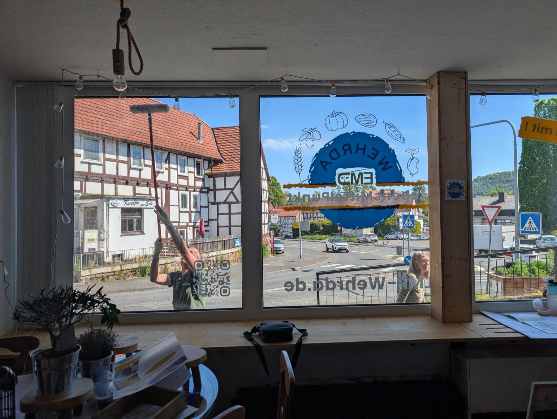 Schaufenster des LebensMittelPunkt Wehrda in der Aufbau-Phase — das Vereinslogo wird aufs Glas gebracht