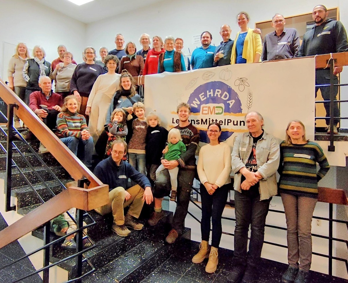 Die Gemeinschaft des LebensMittelPunkt Wehrda — eine große Gruppe auf der Treppe hinter dem Vereinsbanner